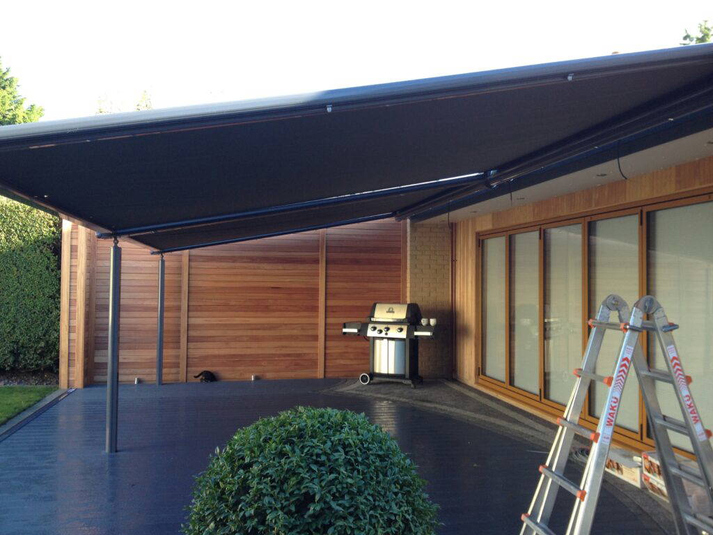 Large Weinor Plaza Viva pergola awning being installed over a cedar-clad garden extension