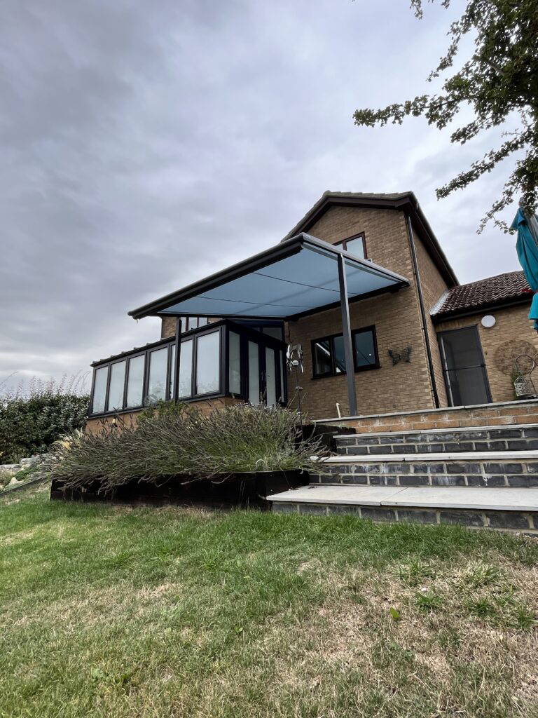 Weinor Plaza Viva pergola awning fitted above a conservatory extension, viewed from the garden