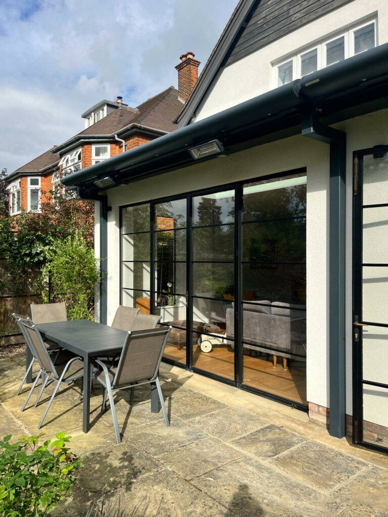 Weinor Opal Design awning installation with wall-mounted heaters and lighting above a garden dining area